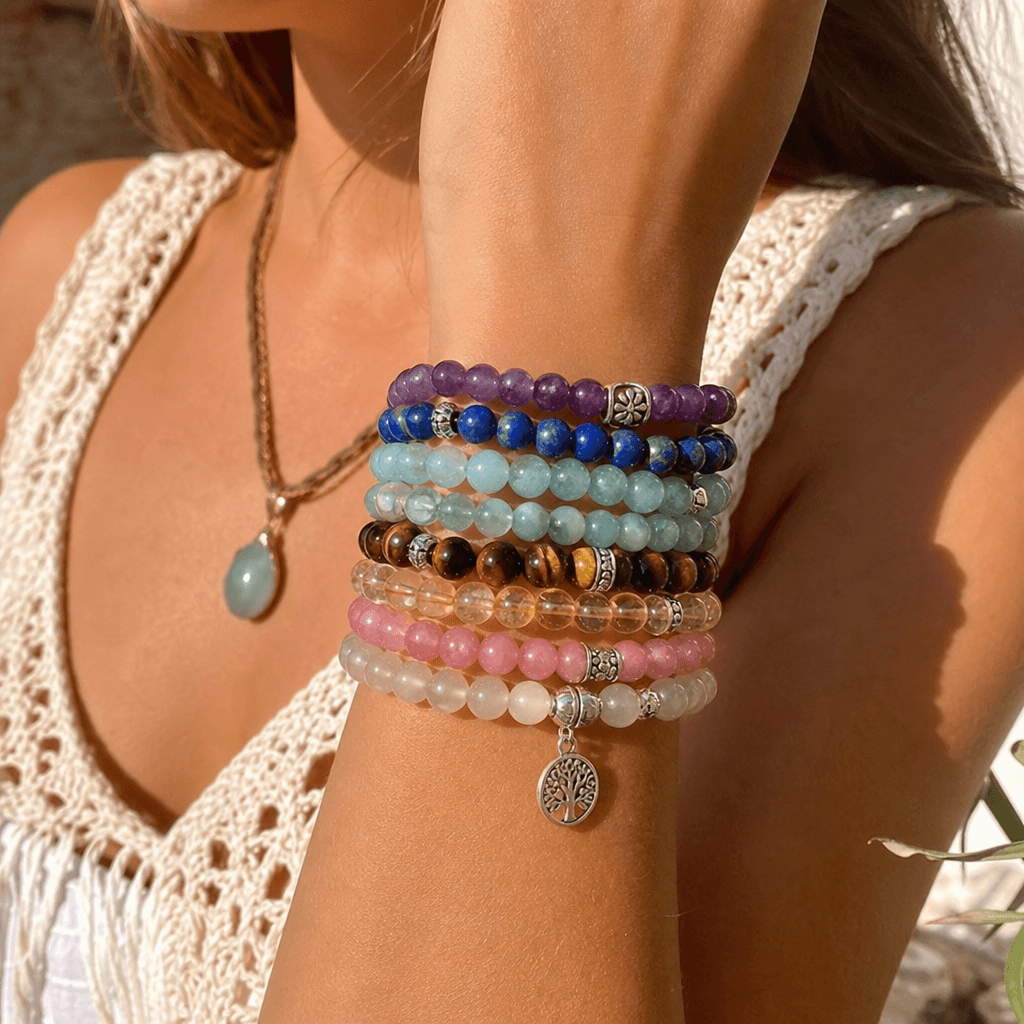 A stack of natural gemstone bracelets worn in sunlight