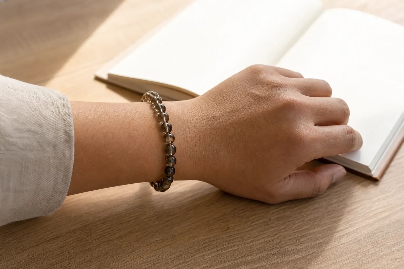 Smoky quartz bead bracelet worn on the left wrist beside an open notebook