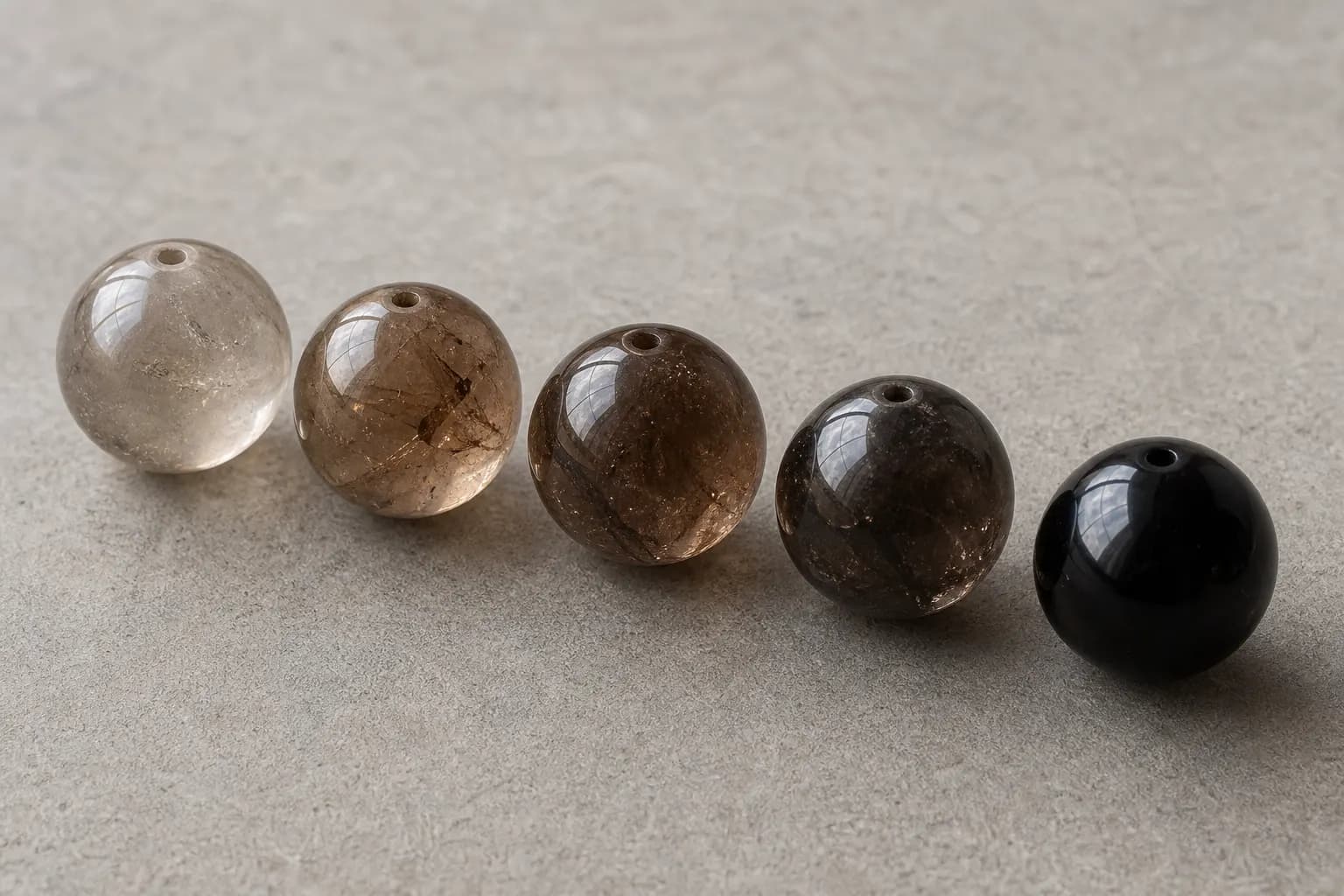 Five smoky quartz beads ranging from pale gray to deep brown-black
