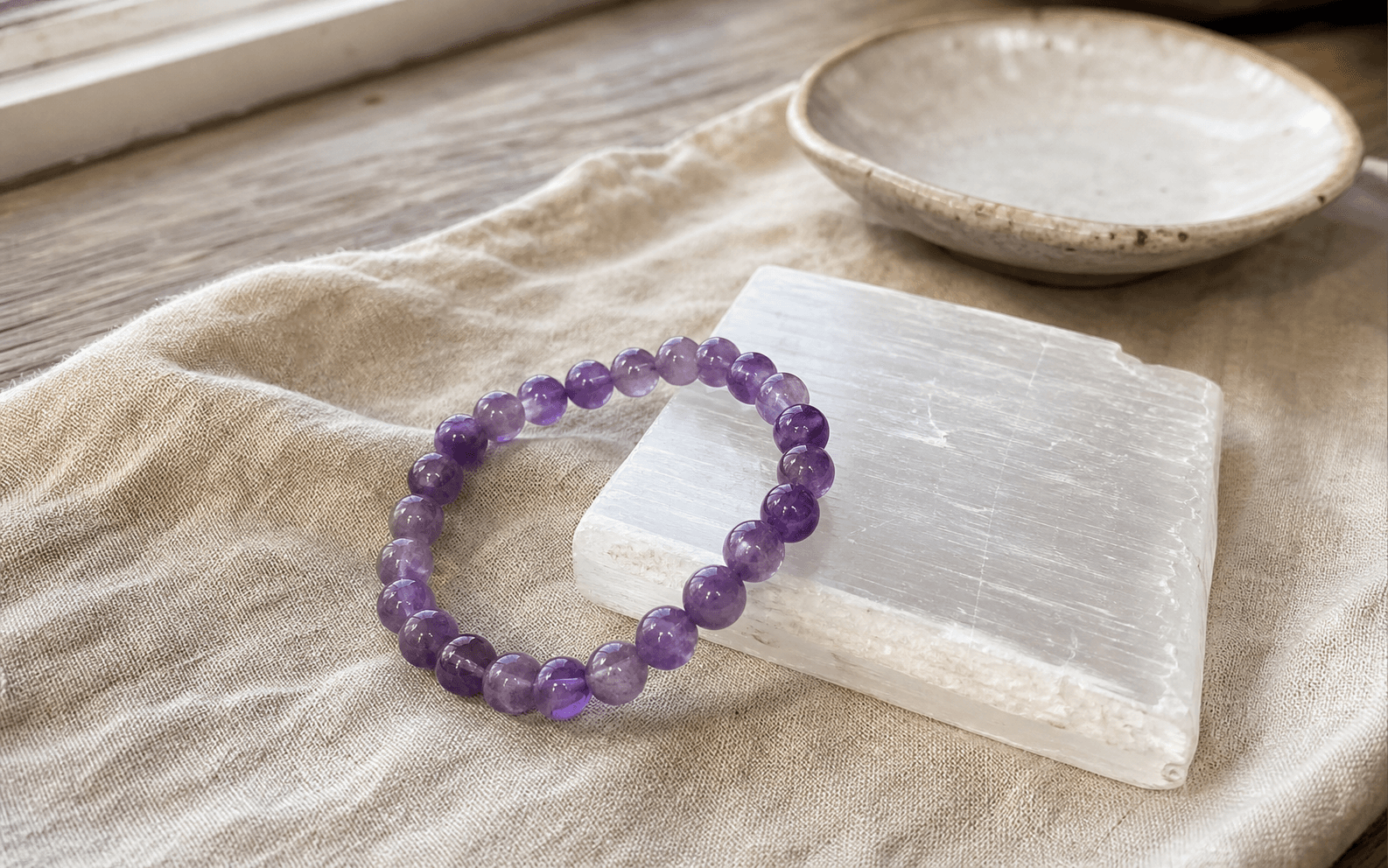 Amethyst bracelet resting on a selenite plate to cleanse