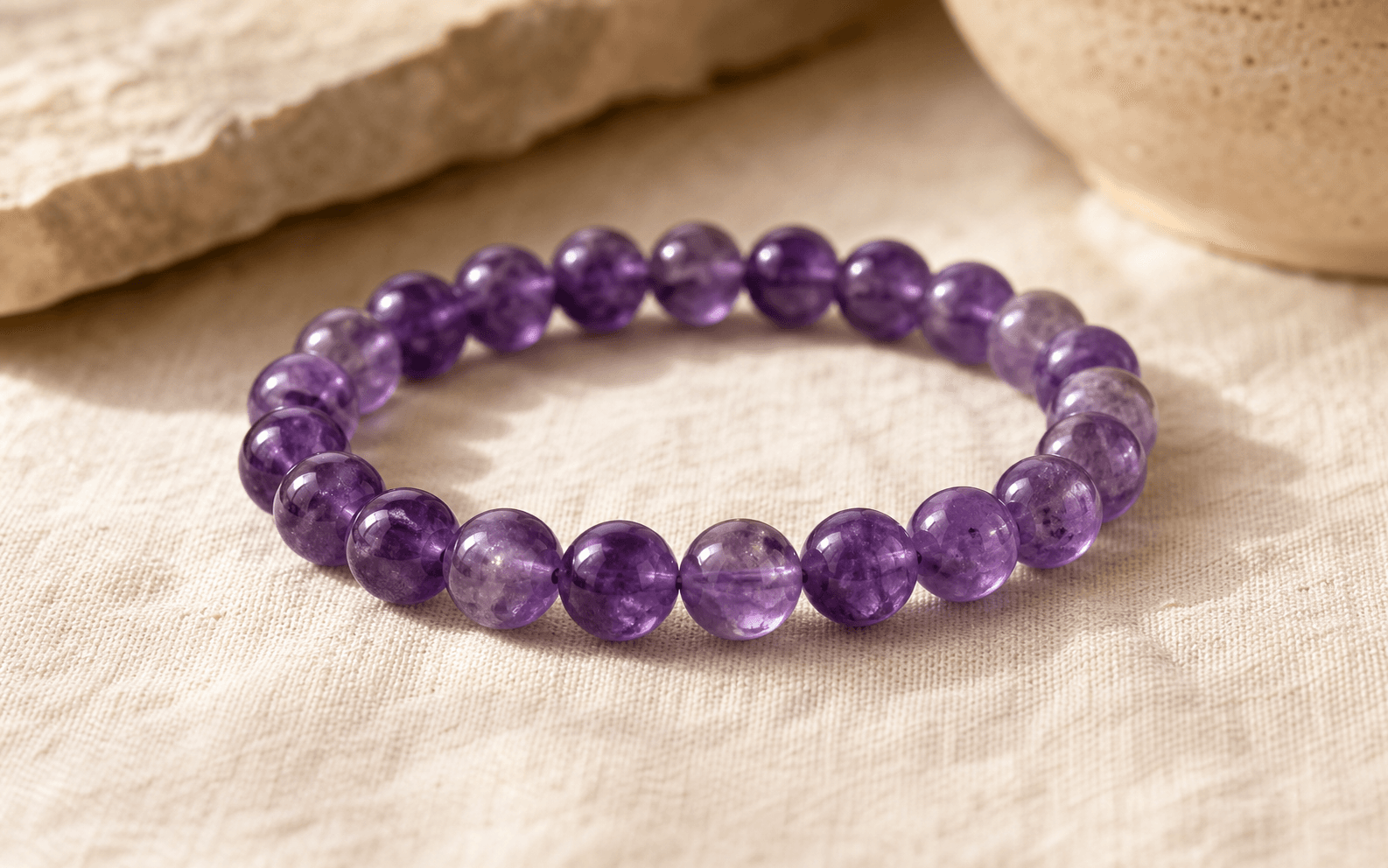 Hand-strung amethyst bead bracelet on pale linen in soft daylight