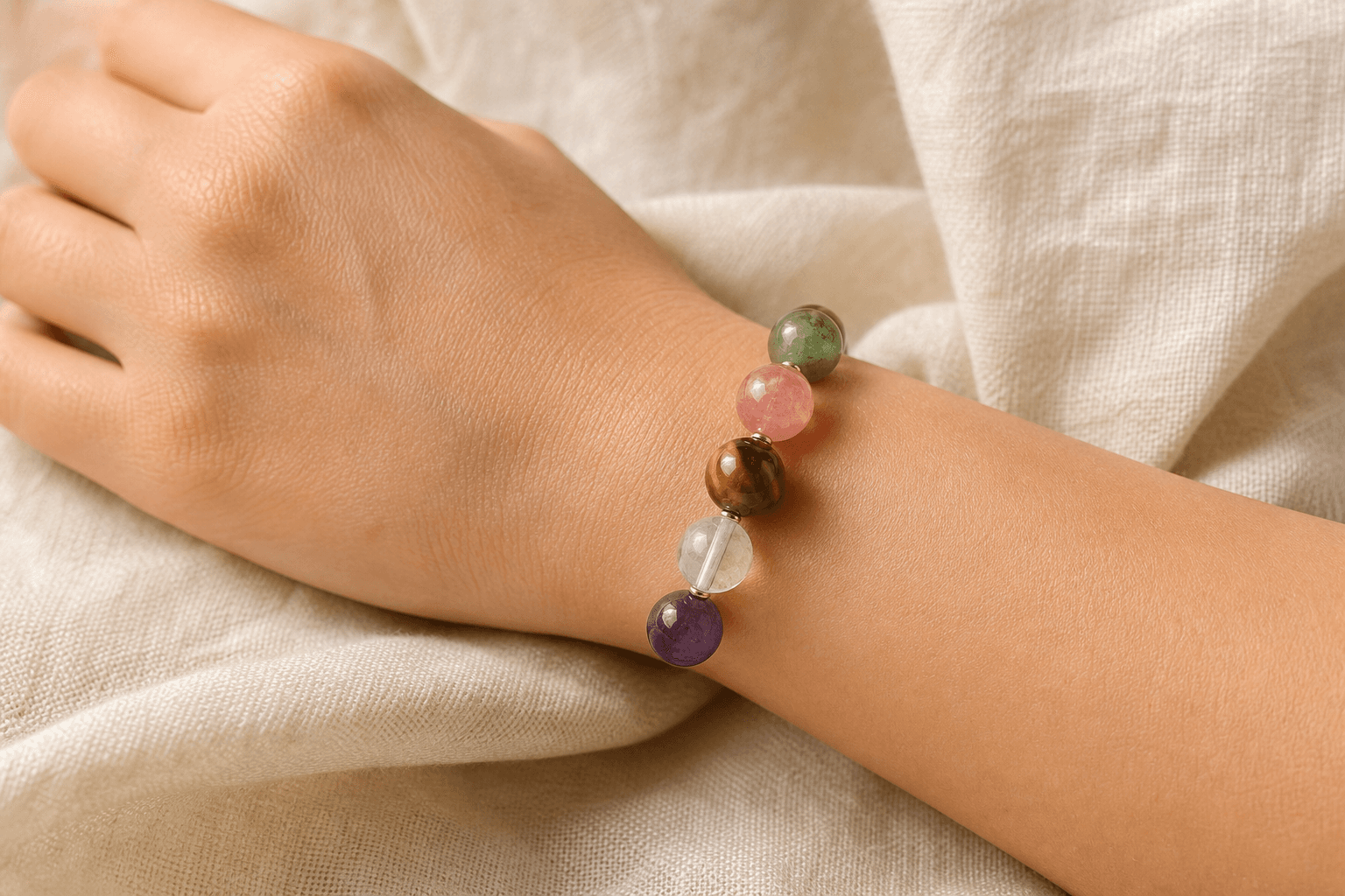 A five-element crystal bracelet worn on the left wrist in soft daylight
